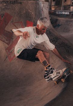 A senior skateboarder skillfully performs a trick in an urban skatepark in Buenos Aires.