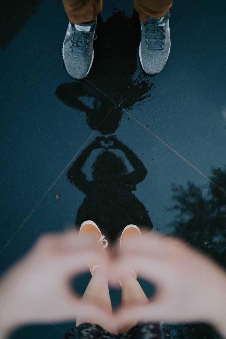 Couple Reflecting In Puddle On Street