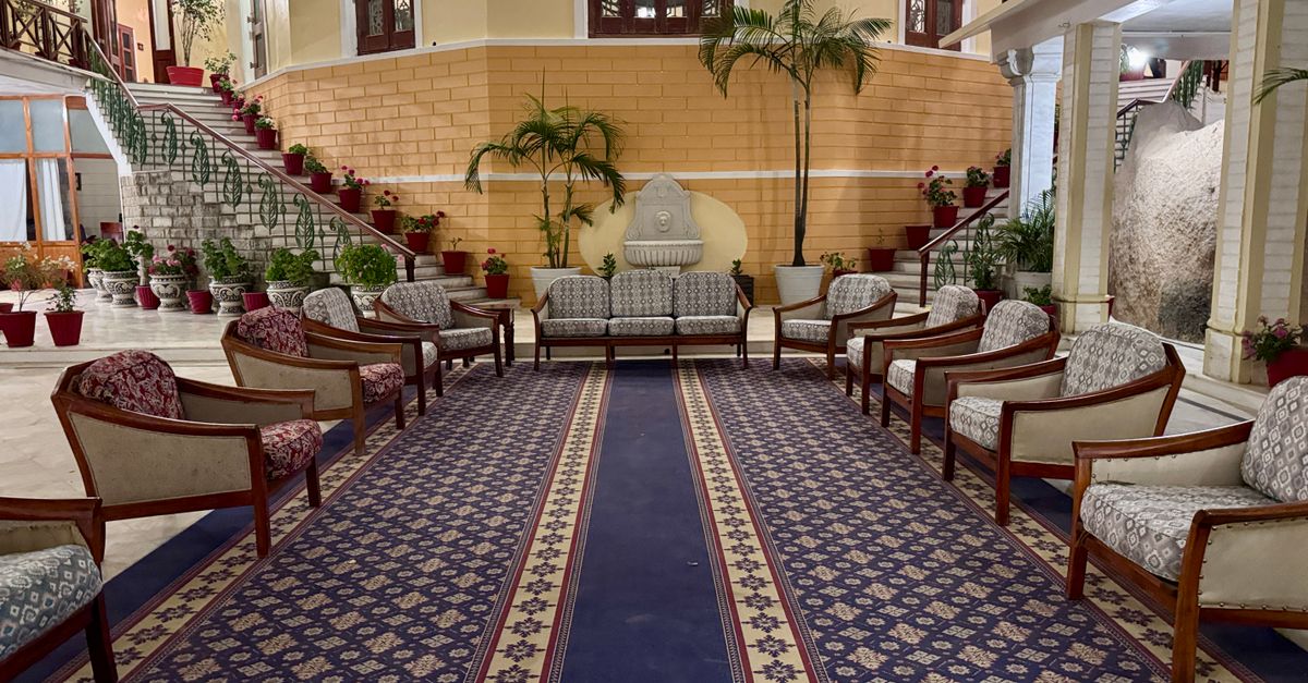 Spacious, elegantly decorated hotel lobby with classic furniture and lush plants.