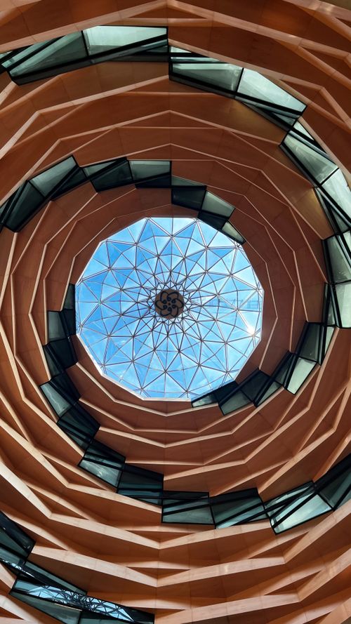 Free Looking up at a modern geometric dome ceiling with sunlight filtering through glass panels. Stock Photo