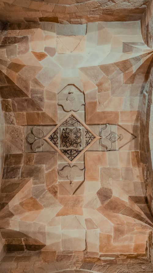 Free Detailed stone ceiling with geometric and floral motifs under warm lighting. Stock Photo