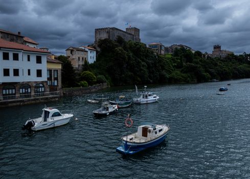 Picturesque scene of boats moored by the coast under a cloudy sky in San Vicente de la Barquera, Spain.