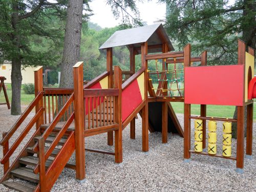 Free Colorful wooden playground set in an outdoor park setting under tall trees. Stock Photo