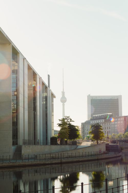 Free A scenic view of Berlin with the iconic TV Tower, city buildings, and River Spree under a bright sky. Stock Photo