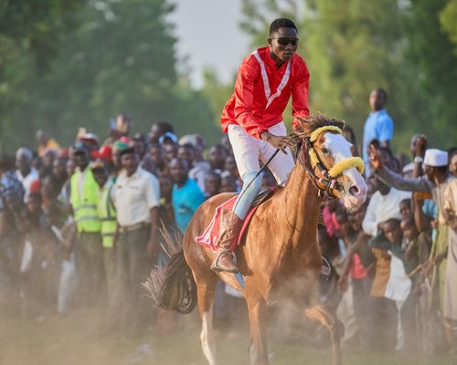 Free Rider in vibrant attire leads a horse race at a cultural event in Zaria City, Nigeria. Stock Photo