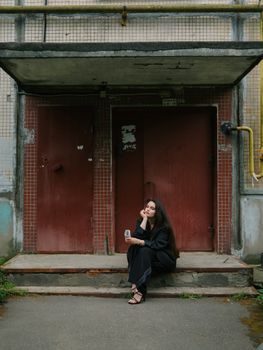 A young woman relaxing on steps in an urban setting, embracing a thoughtful expression.