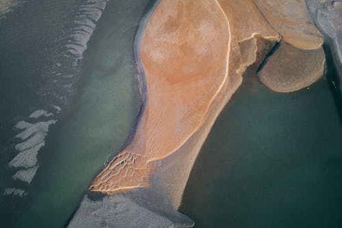 Aerial view of remote line of sand in peaceful water of ocean in sunlight