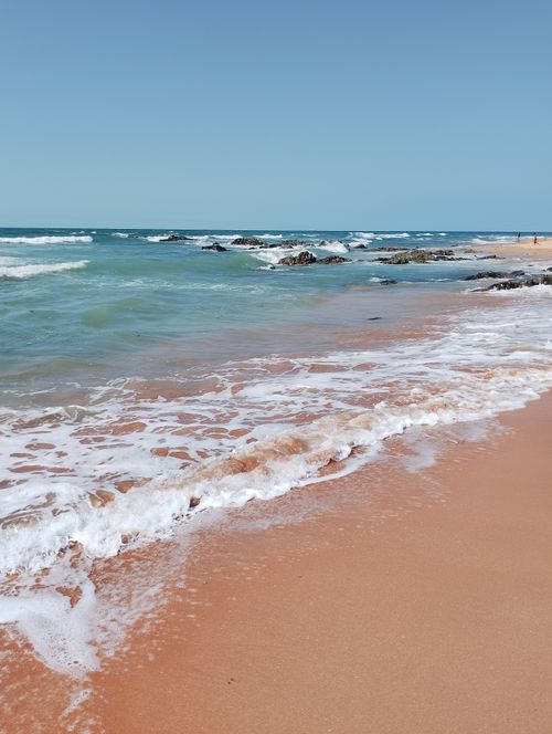 Free Captivating beach scene with gentle waves, clear blue sky, and sandy shoreline. Stock Photo