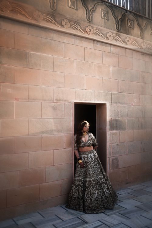 Free A woman in traditional Indian attire leans against an ornate stone wall in a serene setting. Stock Photo