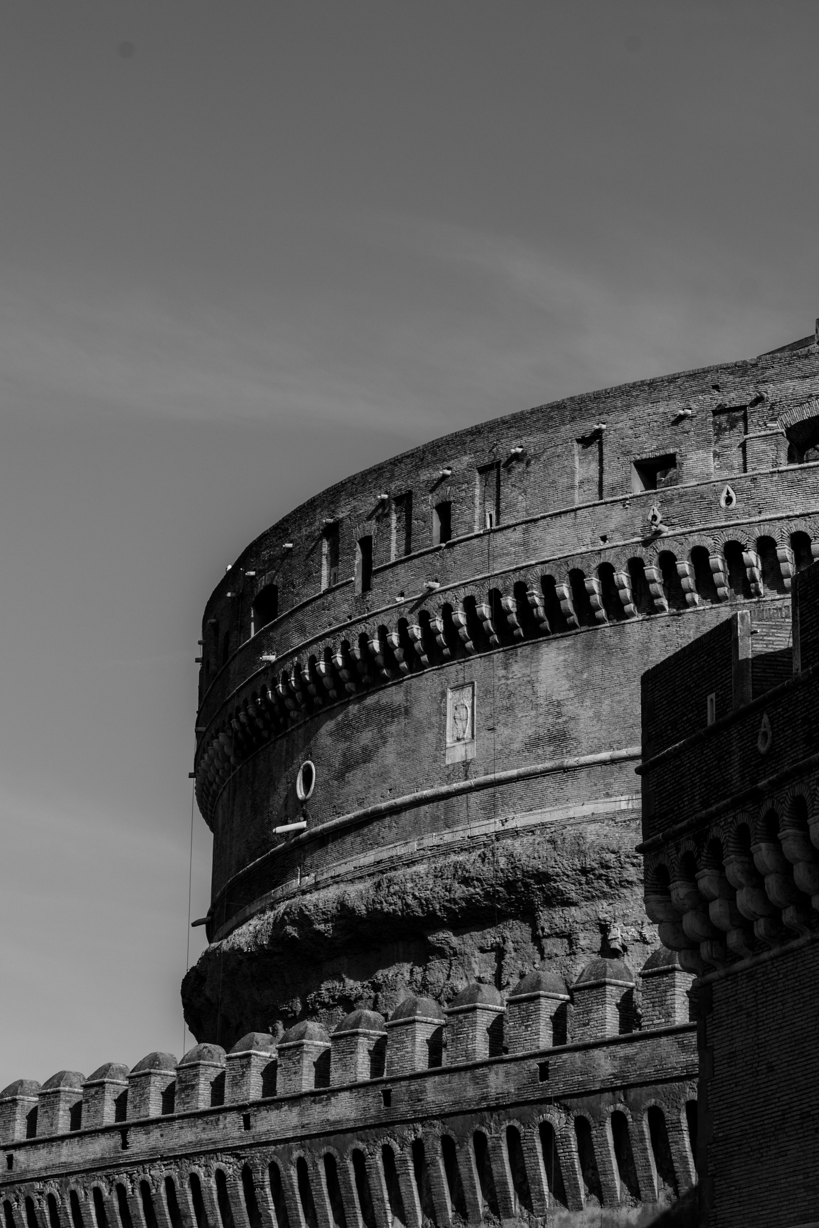Dramatic black and white photograph of Castel Sant'Angelo in Rome, showcasing its majestic architecture.