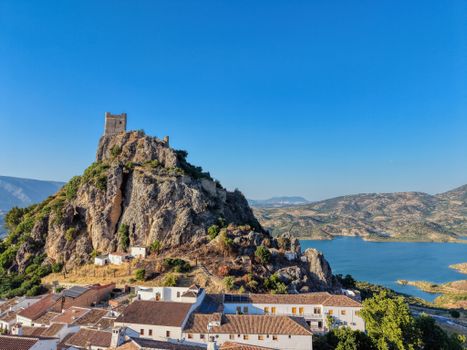 Aerial view of Zahara de la Sierra with its iconic castle overlooking a picturesque lake in Andalucía, Spain.
