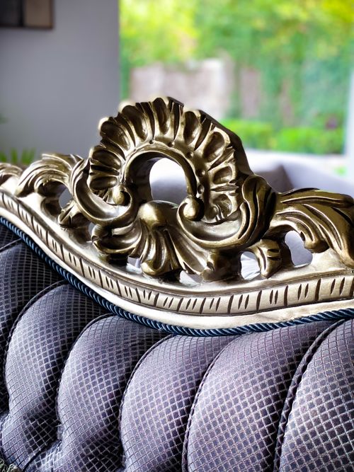 Free Ornate gold headboard with intricate carvings on a plush sofa, bathed in natural light. Stock Photo
