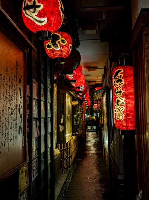 Free Illuminated red Japanese lanterns line a narrow alleyway in Osaka at night. Stock Photo
