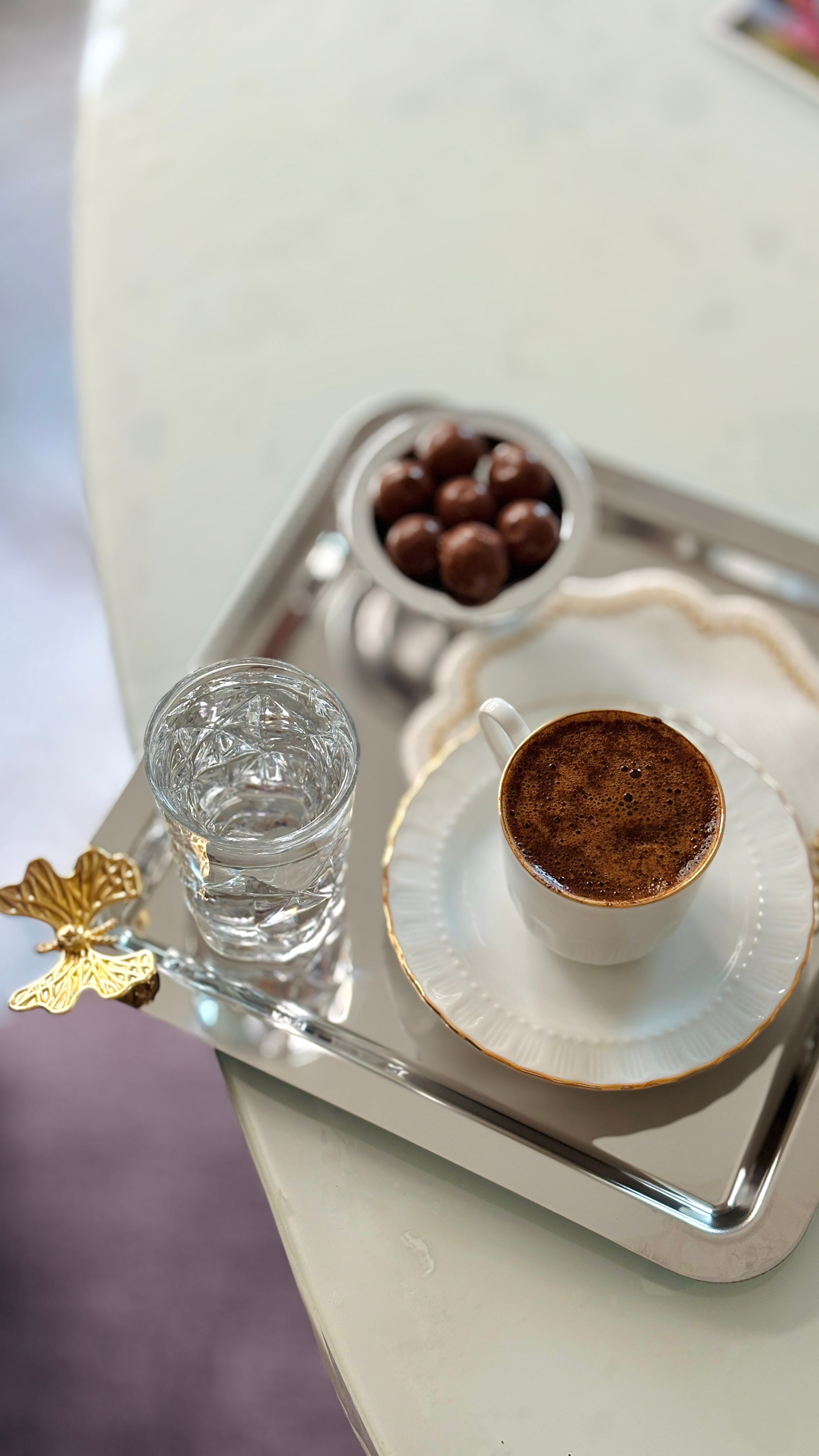 Elegant tray with Turkish coffee, water, and chocolates, highlighting sophisticated serving.