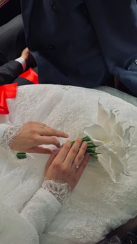 Bride holding a white lily bouquet in elegant lace gown. Captured at a special wedding ceremony.
