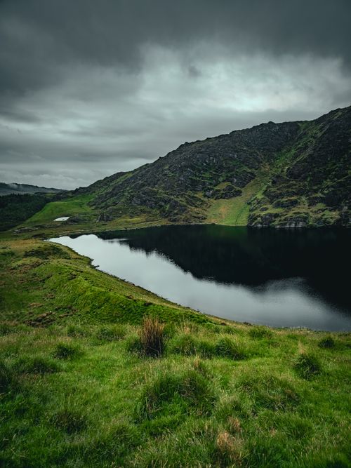 Free Tranquil view of a lake nestled in Ireland's lush green mountains under overcast skies. Stock Photo