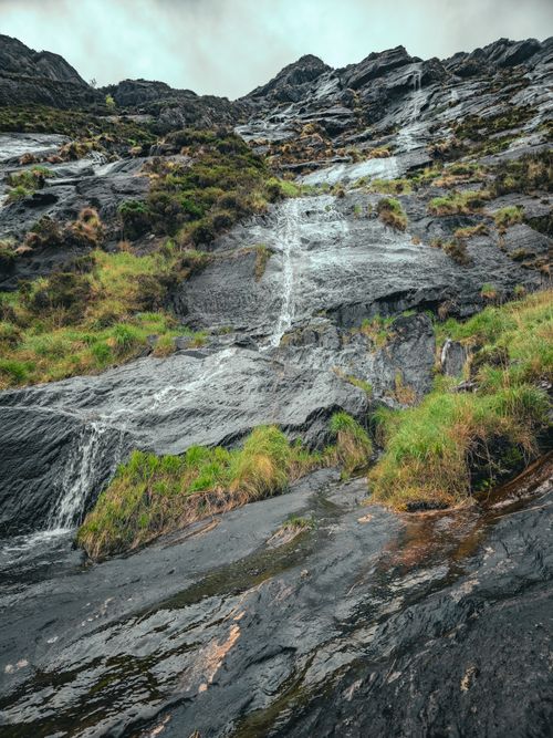 Free Scenic view of a cascading waterfall over rocky terrain with lush greenery in Ireland. Stock Photo