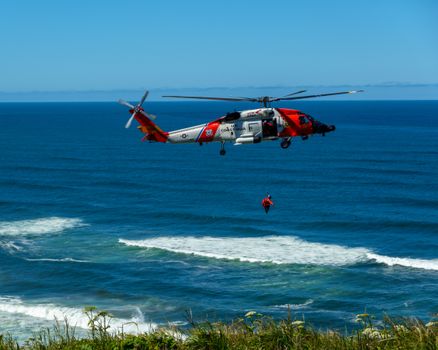 Dramatic coast guard helicopter rescue operation over the ocean waves.