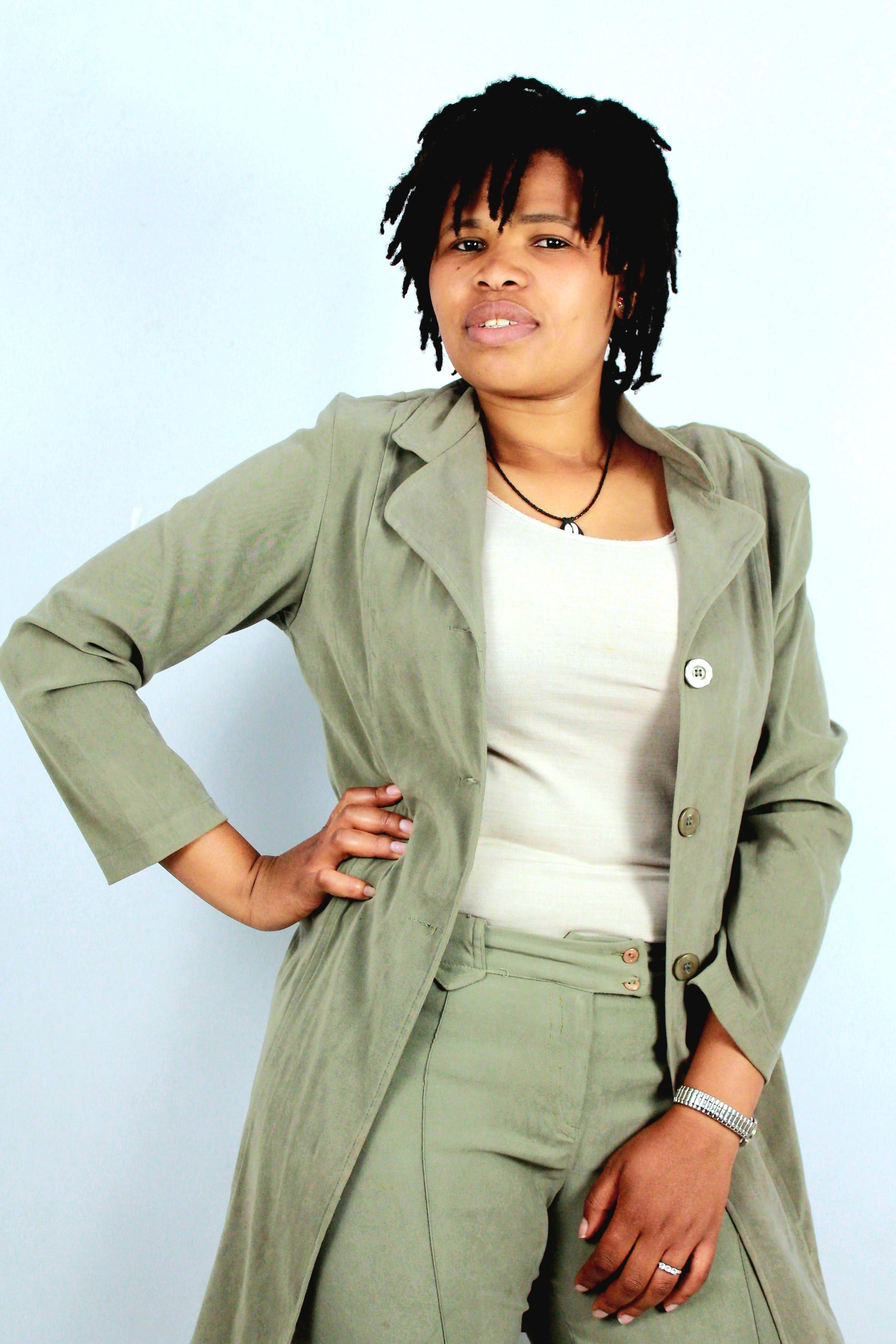 Portrait of a confident woman in casual attire with hands on hips, set against a light background.