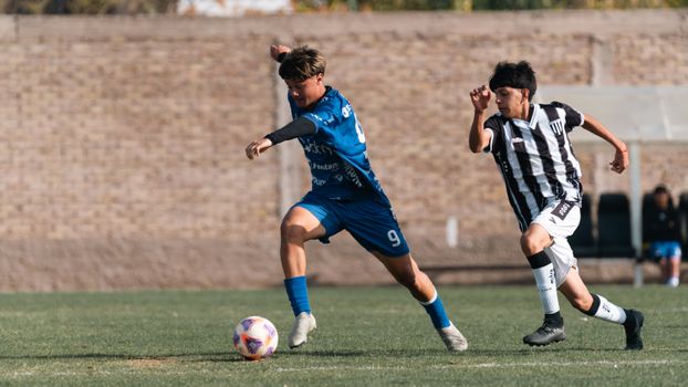 Two young soccer players in action during a competitive outdoor match on a sunny day.