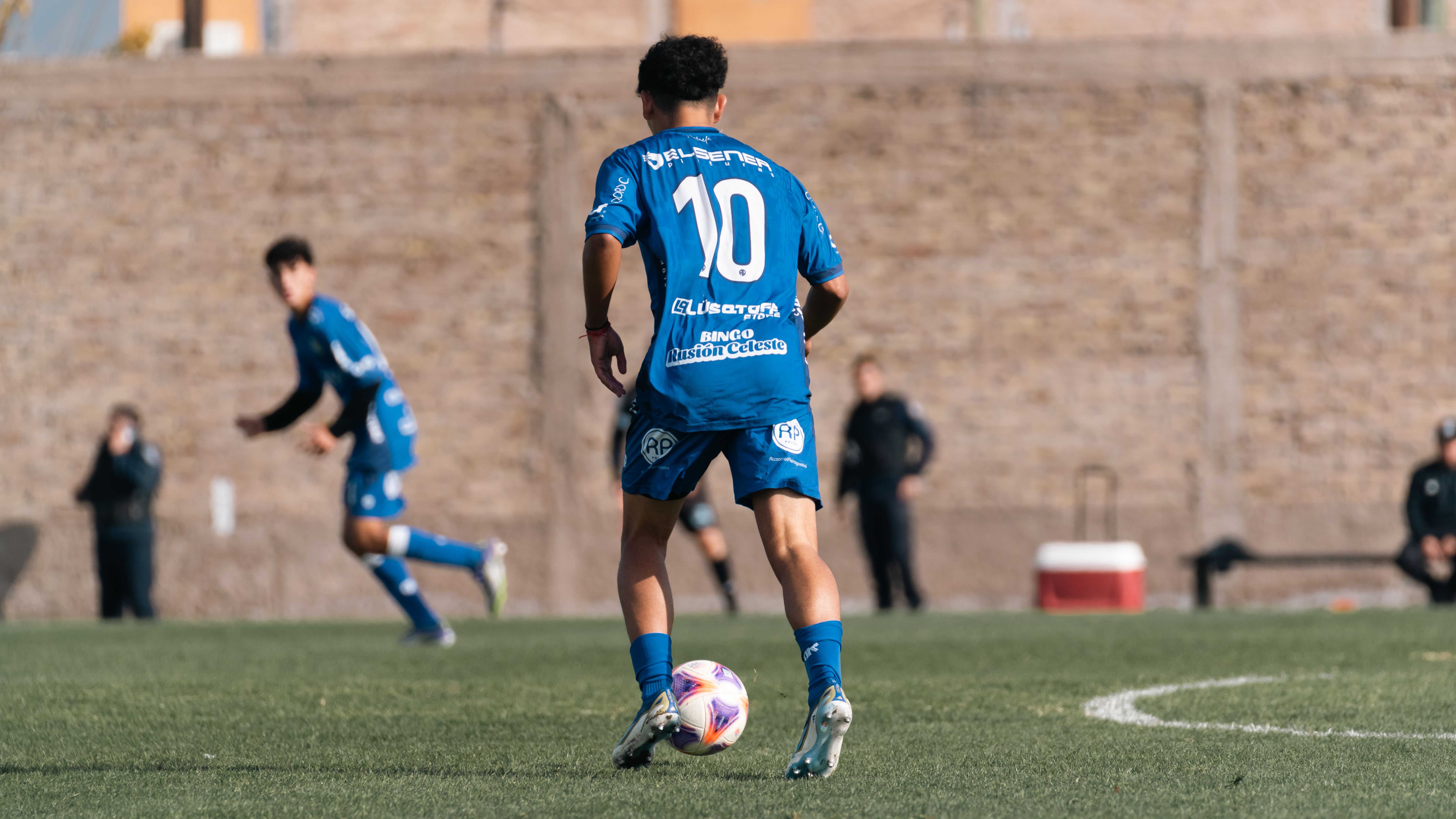 Soccer player wearing number 10 blue jersey during a match on a sunny day.