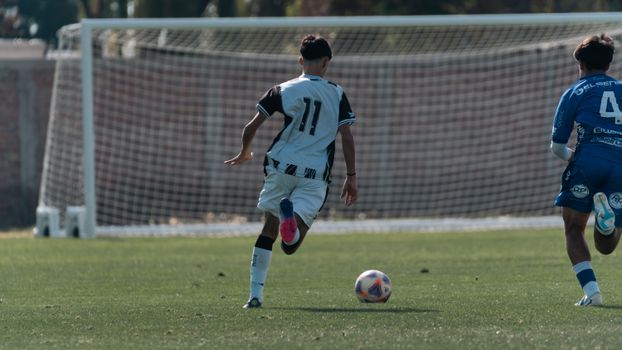 Two young players engaged in a competitive soccer match on a bright sunny day, showcasing athleticism and teamwork.