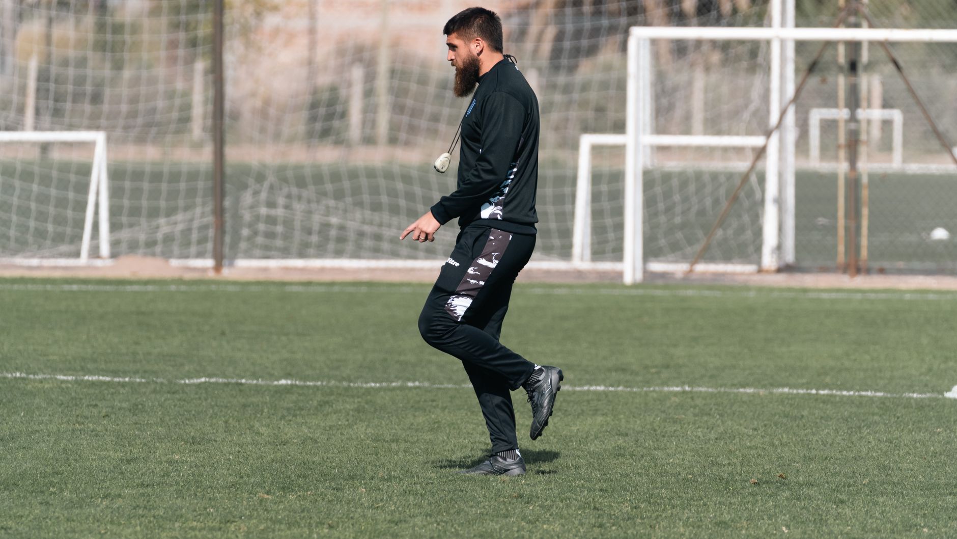 Riyad Mahrez training with Algeria teammates on a sunlit pitch, younger players listening during tactical drills