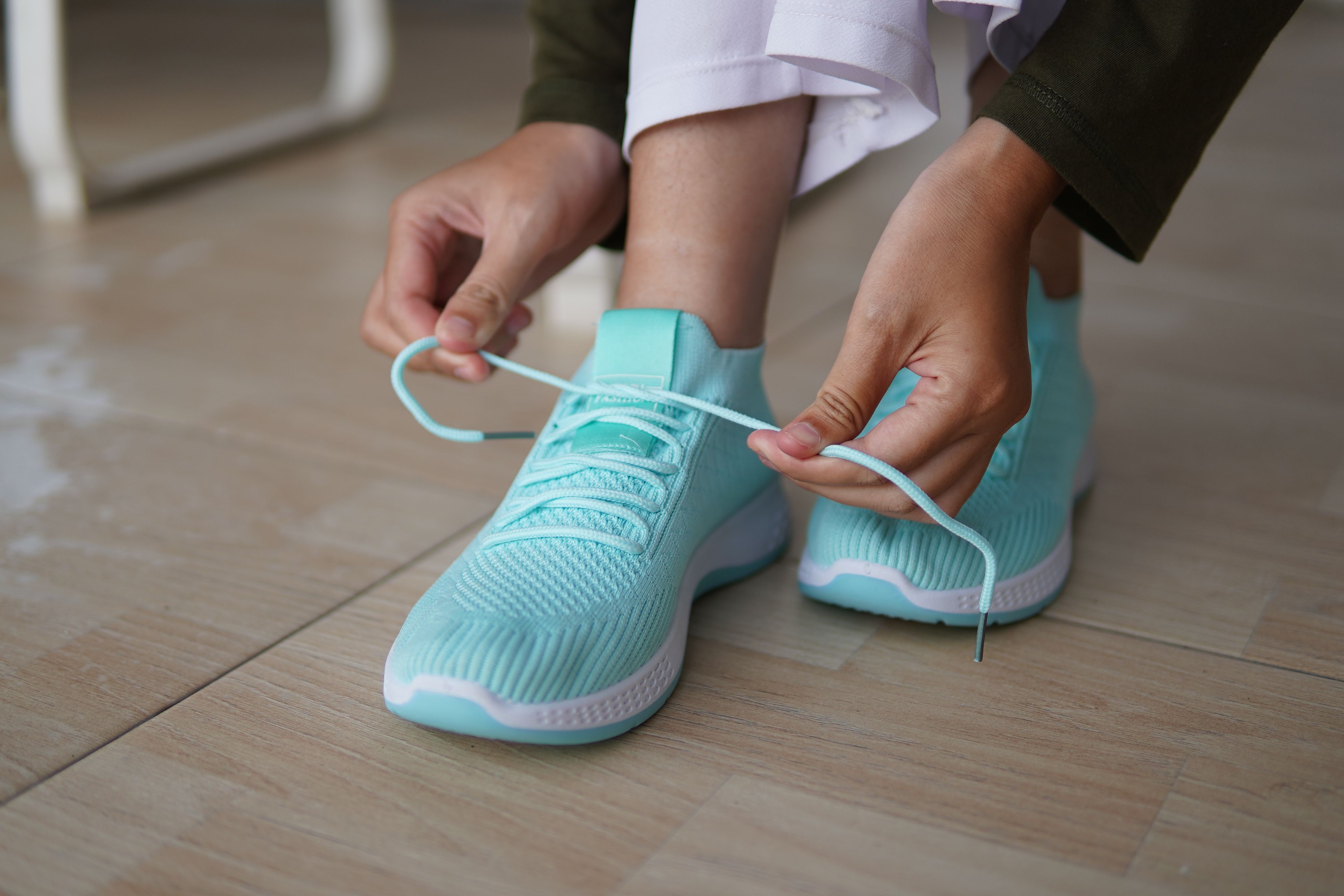 Person Tying Laces of Turquoise Athletic Shoe
