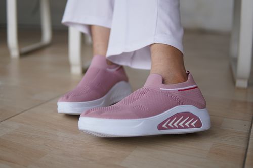 Free Close-up of pink slip-on sneakers worn indoors, showcasing modern design and comfort. Stock Photo