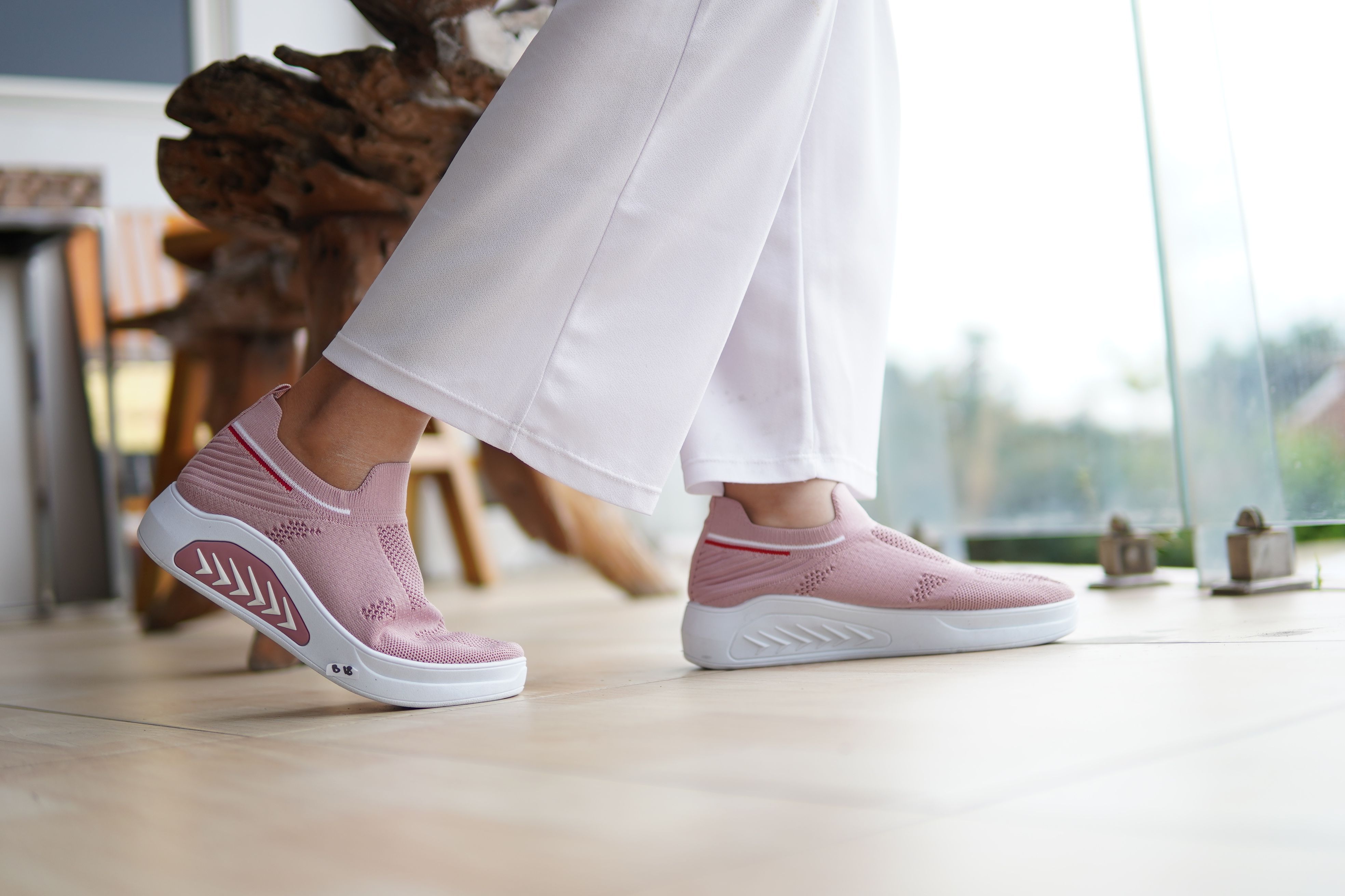 Fashionable pink sneakers paired with white pants, perfect for casual indoor settings.