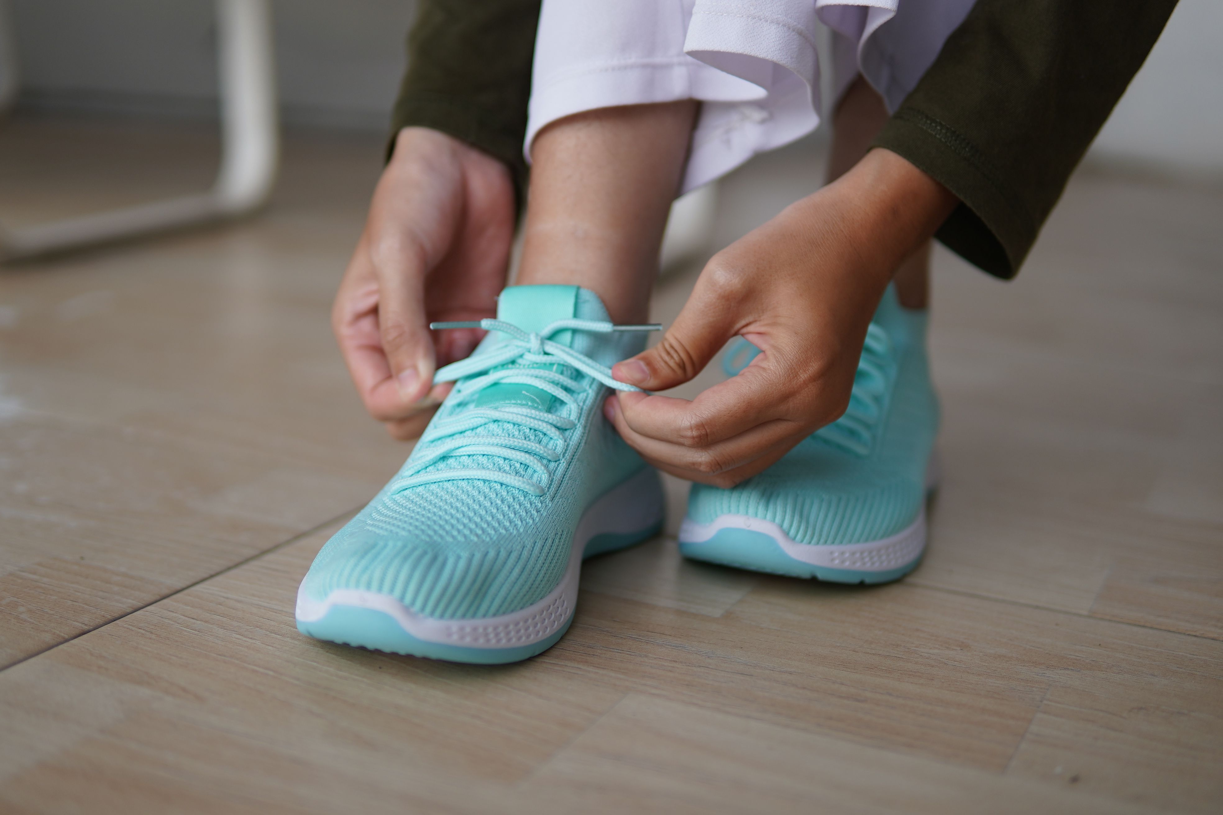 Person tying shoelaces on blue sneakers indoors