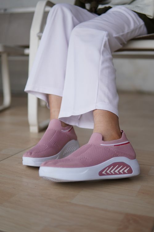 Free Casual style showcasing pink slip-on sneakers paired with white pants indoors. Stock Photo