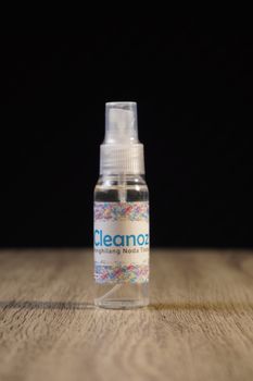 Clear spray bottle with colorful label on wooden surface against dark background. - Fotografer Sidoarjo