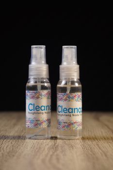 Two bottles of Cleanox stain remover on a wooden surface with a black background. - Fotografer Sidoarjo