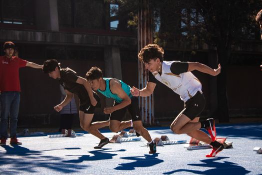 Dynamic action of male athletes sprinting from starting blocks on an outdoor track.