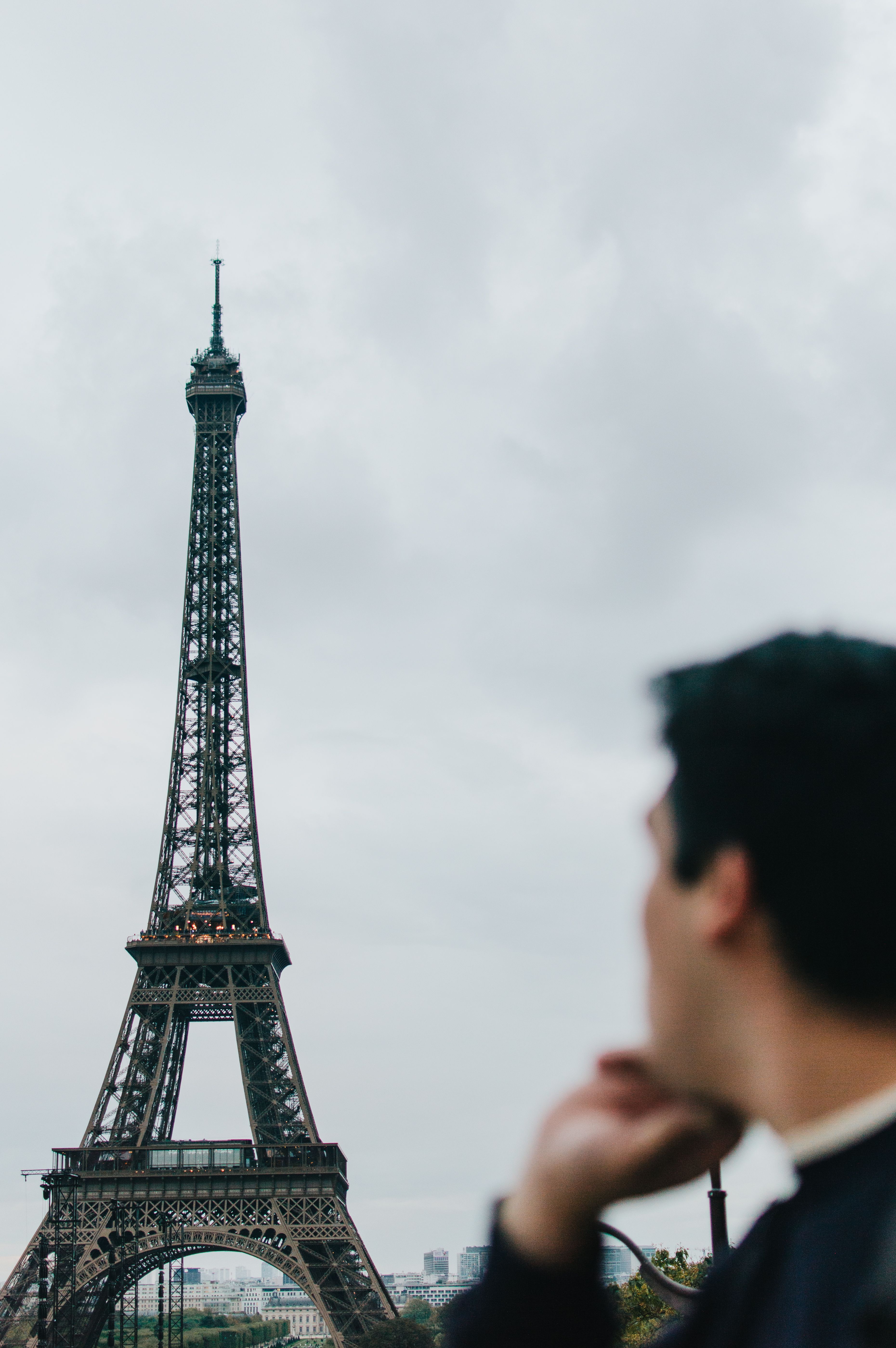 Man viewing the iconic Eiffel Tower on a cloudy day in Paris, France.