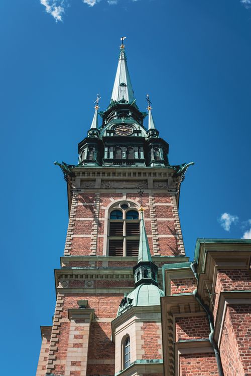 Free A towering brick church spire against a clear blue sky, showcasing Gothic architecture in Stockholm. Stock Photo
