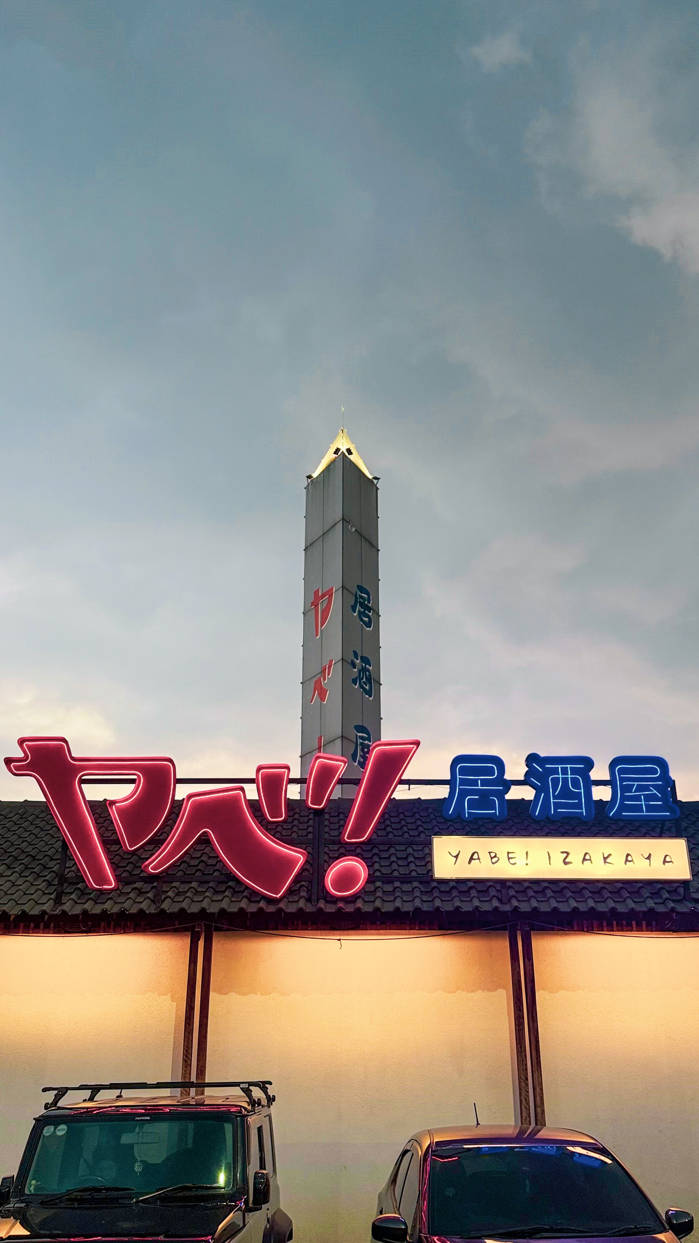 Neon signage of Yabe Izakaya lit up against the evening sky in Bandung, Indonesia.