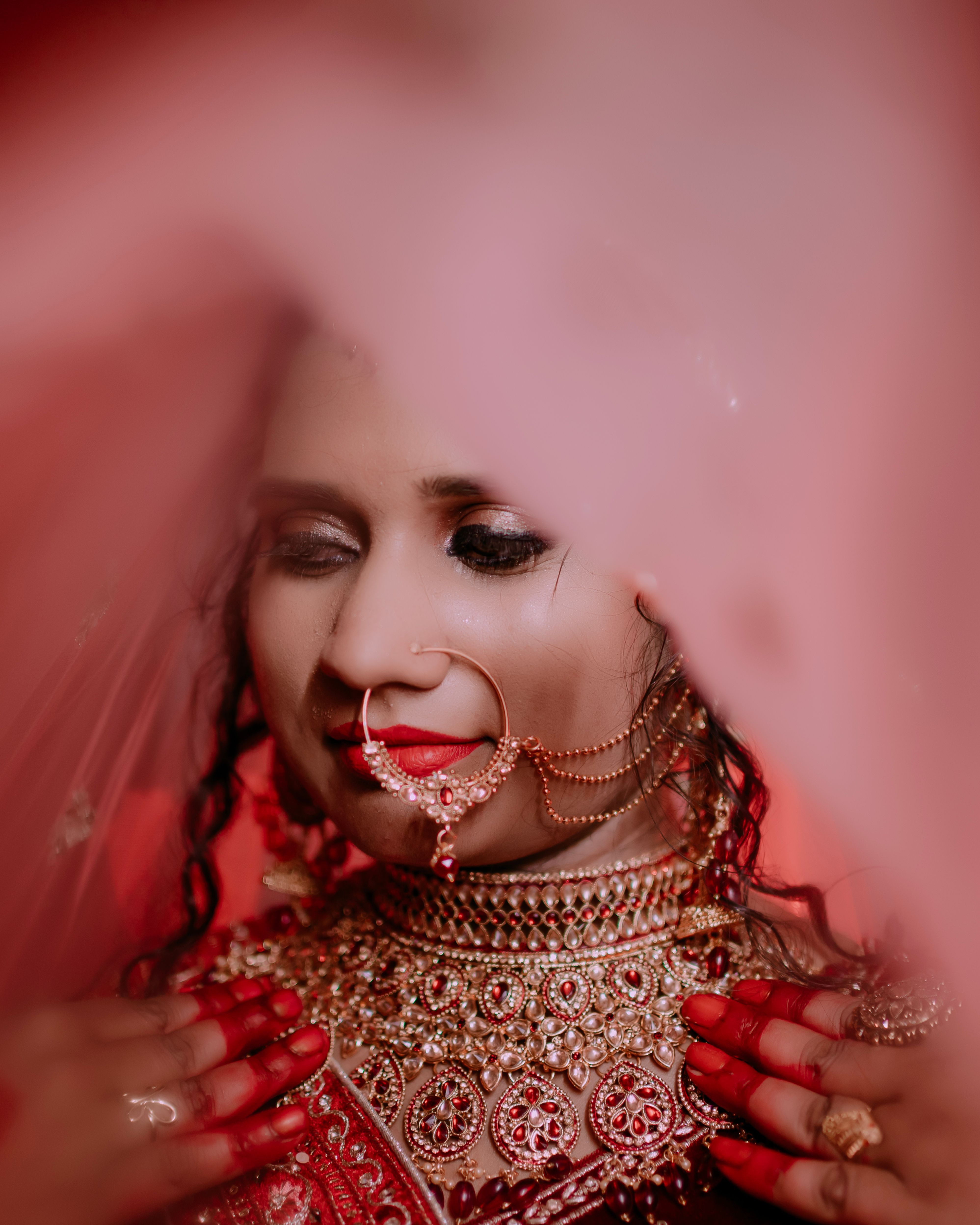 Beautiful South Asian bride adorned in traditional red bridal lehenga with intricate jewelry.