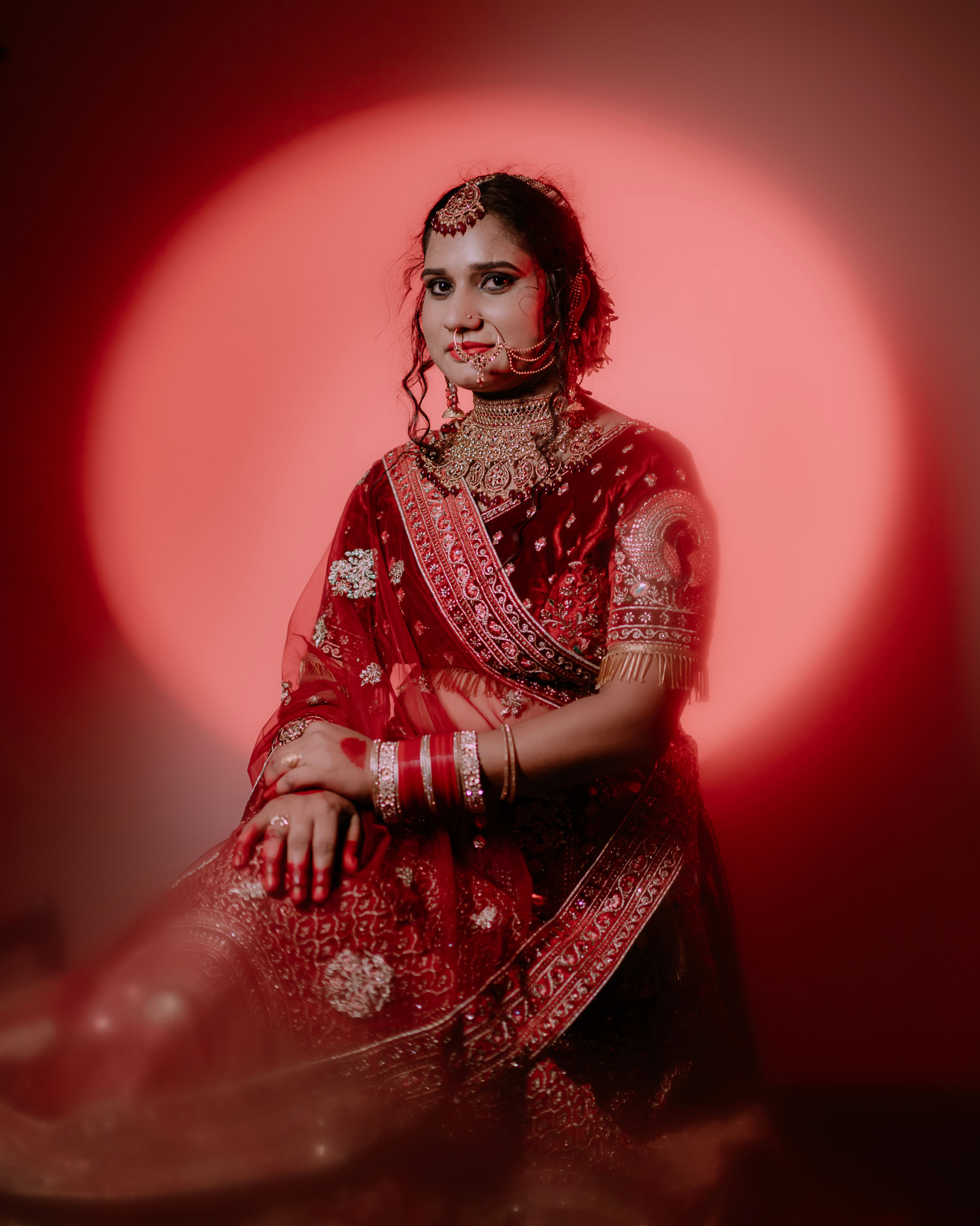 A stunning portrait of a bride in a vibrant red sari, showcasing intricate embroidery and traditional jewelry.
