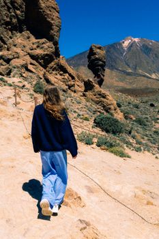 A woman hiking through the striking landscape of Teide National Park, Spain, under a clear blue sky.