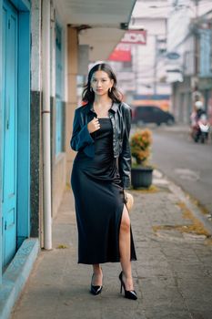 Fashionable woman in black dress walking along a Bandung street, Indonesia.
