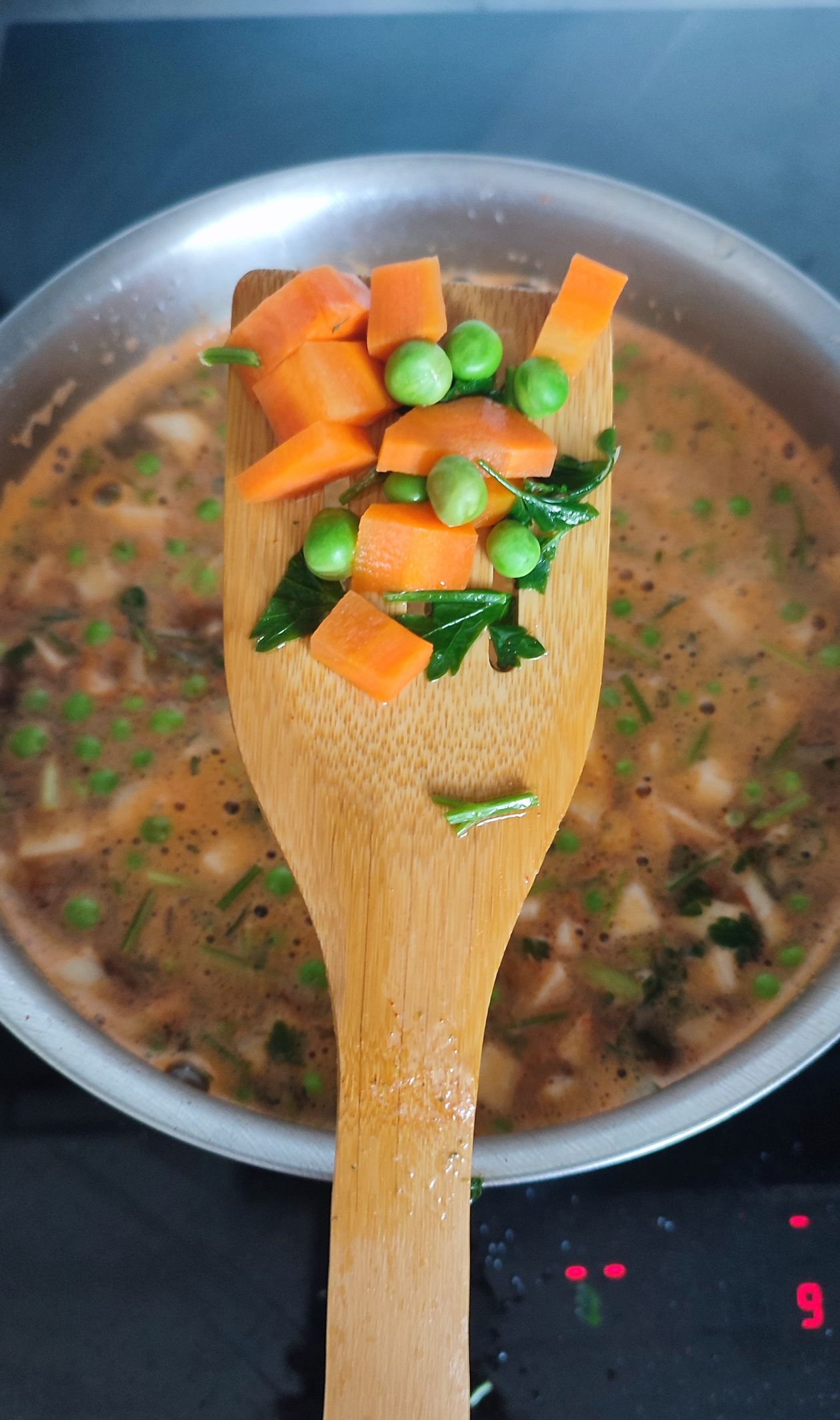 Homemade vegetable beef soup - hearty version simmering in a Dutch oven with fresh vegetables on wooden spoon