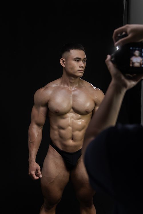 Free Muscular bodybuilder captured in a dramatic studio pose. Fitness, strength, and physique concept. Stock Photo