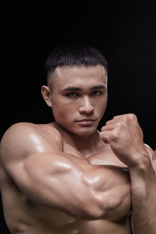 Free Muscular male bodybuilder posing confidently against a dark background. Stock Photo