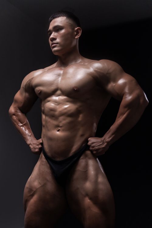 Free Strong bodybuilder showcases powerful physique with dramatic lighting for fitness inspiration. Stock Photo