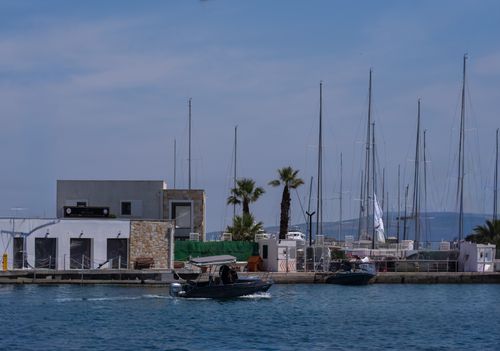 Free Scenic harbor in Foça, İzmir with boats, palms, and blue sky. Stock Photo