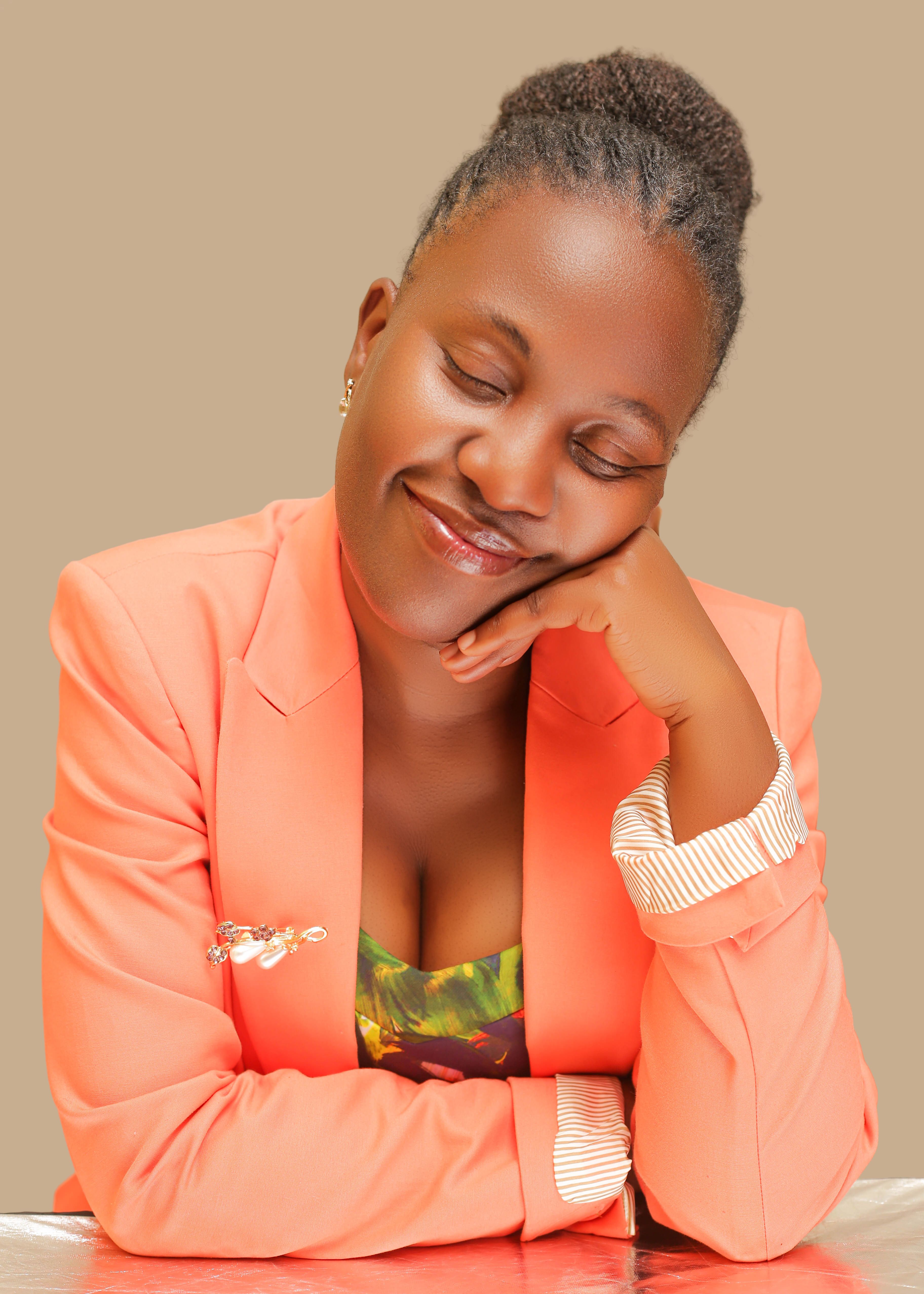 A serene portrait of a woman in a coral blazer, resting her head on her hand with eyes closed.