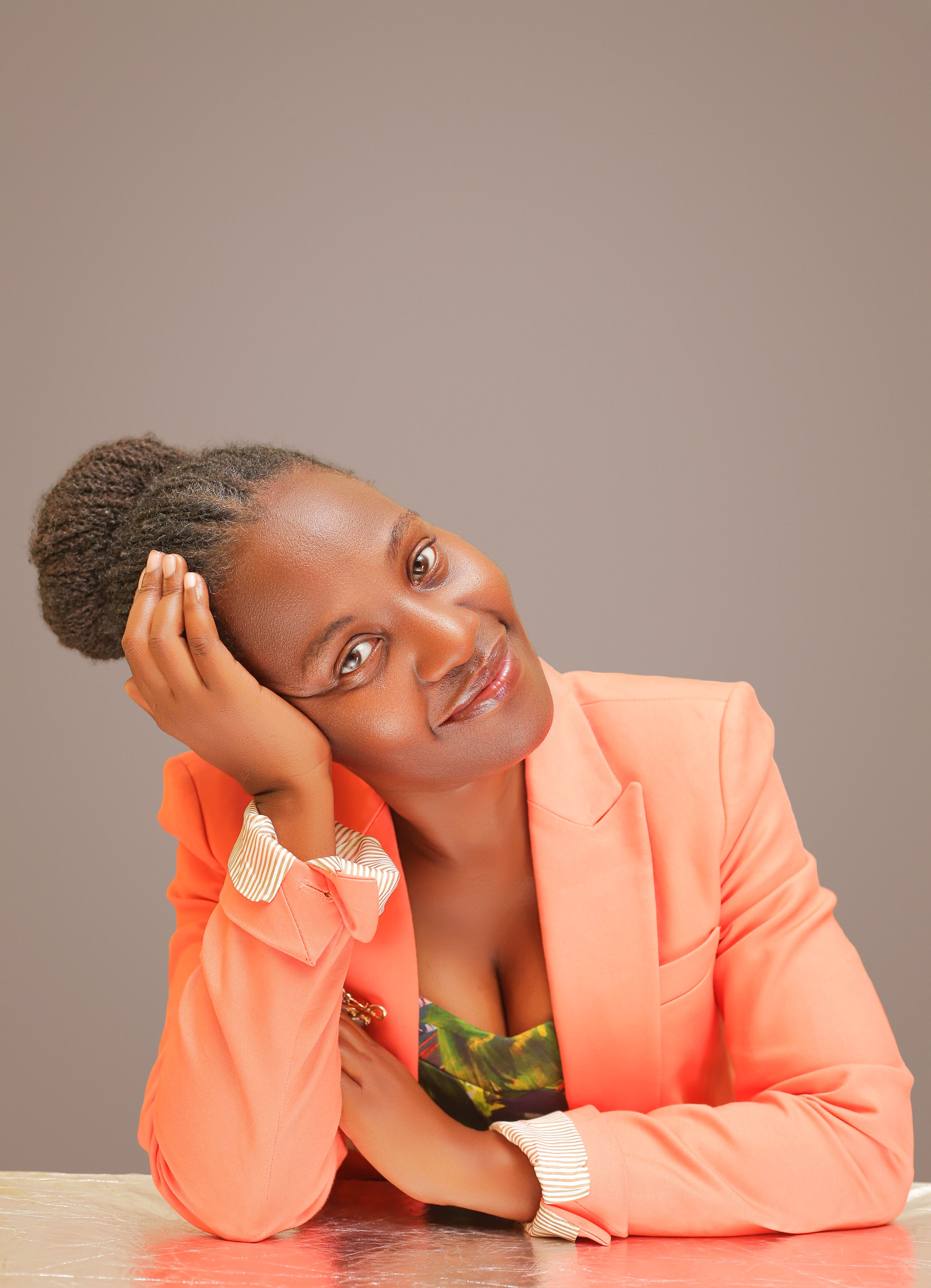 Portrait of a smiling woman in a stylish peach blazer against a neutral background.