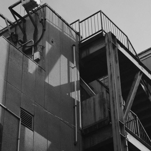 Free A black and white photo capturing a building's industrial exterior with stairs. Stock Photo